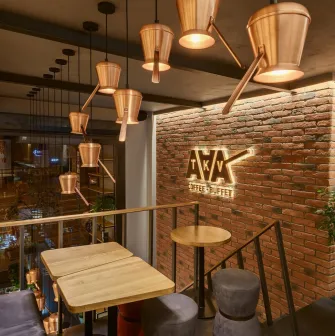 Takava in Kyiv - mezzanine seating with copper cezve lamps and brick wall logo