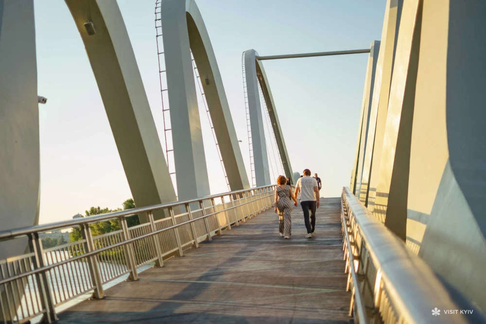 Couple walking on wavy bridge in Kyiv
