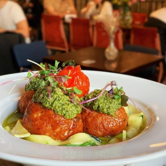 Restaurant Zigzag - meatballs topped with pesto and a roasted tomato on a plate