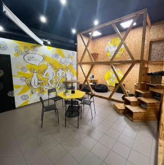 Muzei u Temriavi in Kyiv - modern waiting area designed with wooden structures and yellow accents featuring bean bag chairs for visitors