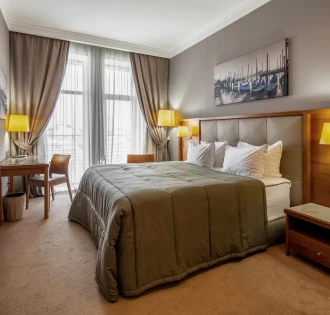 City Hotel in Kyiv - bedroom interior with double bed, painting and desk by the window