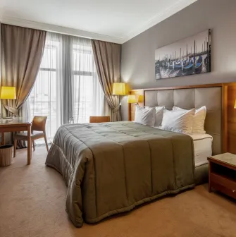 City Hotel in Kyiv - bedroom interior with double bed, painting and desk by the window