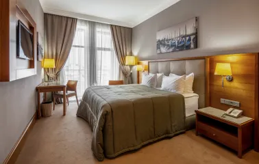 City Hotel in Kyiv - bedroom interior with double bed, painting and desk by the window