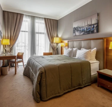 City Hotel in Kyiv - bedroom interior with double bed, painting and desk by the window