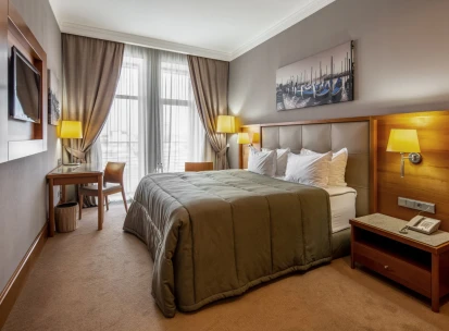 City Hotel in Kyiv - bedroom interior with double bed, painting and desk by the window