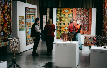 Ukrainskyi Dim in Kyiv - visitors viewing colorful traditional carpets and ceramic menorahs at an exhibition