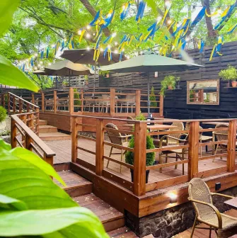 Outdoor restaurant terrace with wooden tables and yellow-blue ribbons
