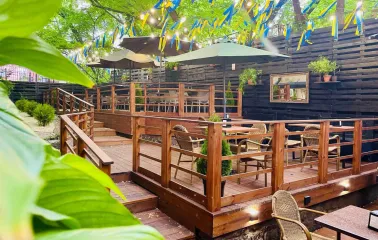 Outdoor restaurant terrace with wooden tables and yellow-blue ribbons
