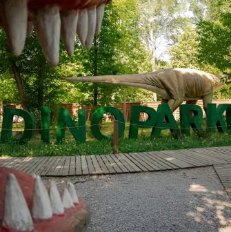 Напис #DINOPARKKYIV на тлі дерев та дерев'яної доріжки в Гідропарку