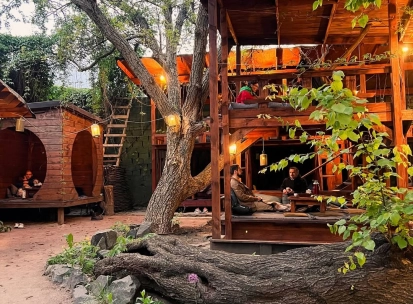 Chaguan in Kyiv - wooden two-story outdoor terrace structure among trees with guests