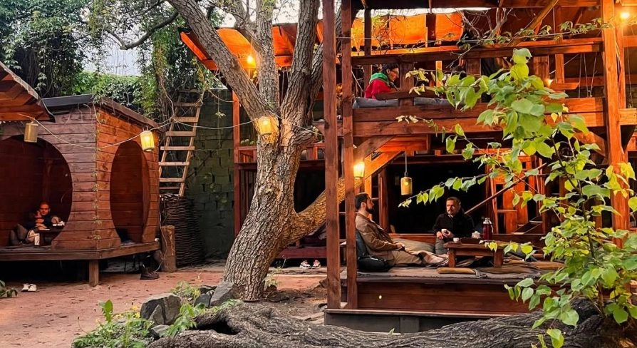 Chaguan in Kyiv - wooden two-story outdoor terrace structure among trees with guests