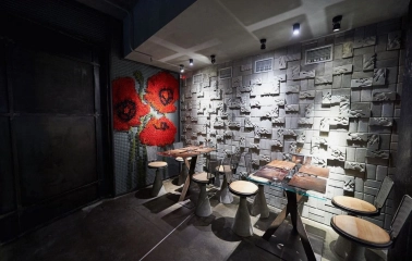 Restaurant Ostannia Barykada - small dining area with poppy flower art and a textured concrete wall