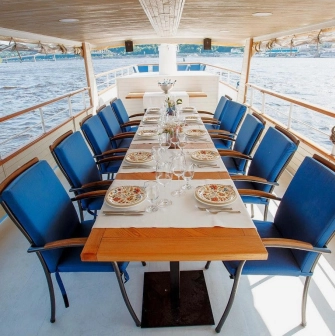 Restaurant Khutorets na Dnipri - table set for a meal on a river boat deck with blue chairs