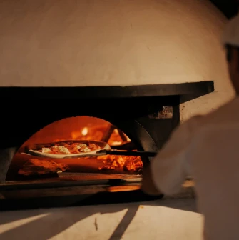 Restaurant Tisto, Syr i Titka Bella - chef placing a pizza inside a wood-fired stone oven