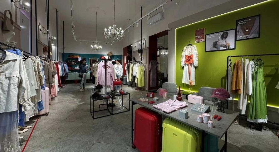 Kapsula in Kyiv - bright and spacious showroom interior with high ceilings and crystal chandeliers displaying racks of fashionable clothes and suitcases