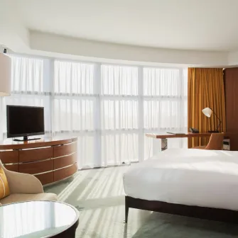 Deluxe room at Hilton Kyiv with a king-size bed, sofa and panoramic windows with yellow curtains