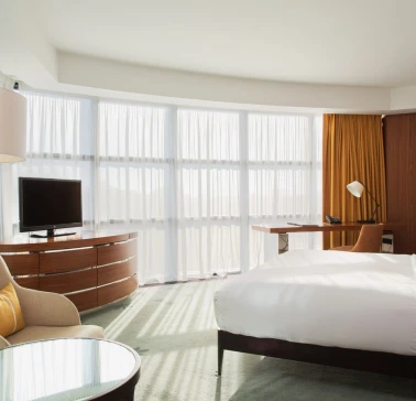 Hilton Kyiv photos showcasing Deluxe room at Hilton Kyiv with a king-size bed, sofa and panoramic windows with yellow curtains