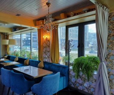 Restaurant Kukhnya Polli - bright and cozy dining room with simple wooden tables and large windows