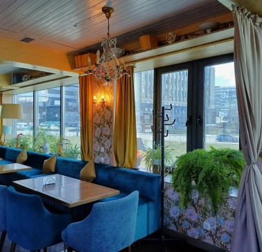 Restaurant Kukhnya Polli - bright and cozy dining room with simple wooden tables and large windows