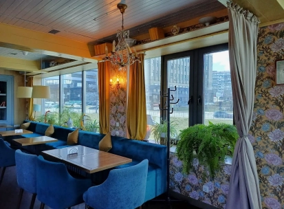 Restaurant Kukhnya Polli - bright and cozy dining room with simple wooden tables and large windows