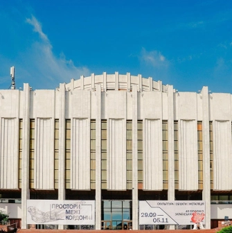 Ukrainskyi Dim in Kyiv - massive white modernist building with vertical lines and flags against the blue sky