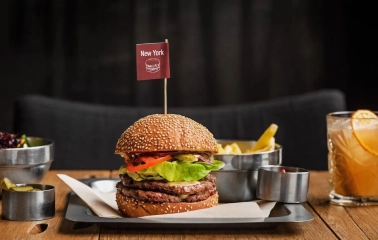 The Burger - close-up view of a signature New York burger served with fries and sauce