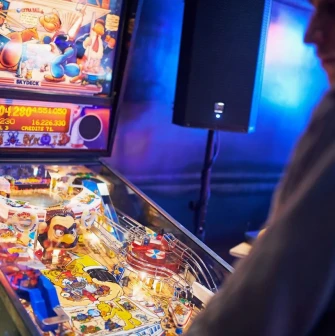Punkraft - man playing pinball machine in neon-lit bar