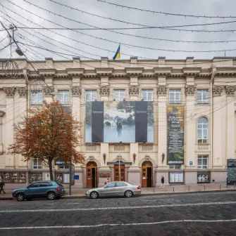 Teatr Lesi Ukrainky in Kyiv - grand historic facade of the theater featuring massive beige columns and a Ukrainian flag on the roof