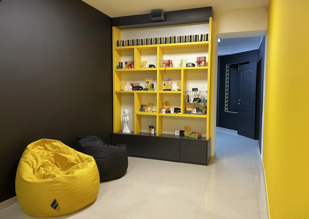 Muzei u Temriavi in Kyiv - bright yellow shelving unit displaying souvenirs and merchandise in a cozy reception area with bean bags