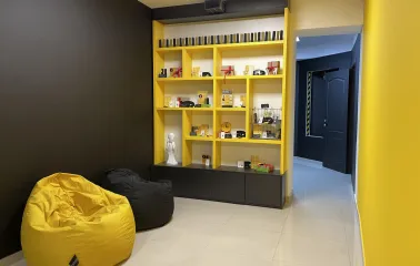 Muzei u Temriavi in Kyiv - bright yellow shelving unit displaying souvenirs and merchandise in a cozy reception area with bean bags