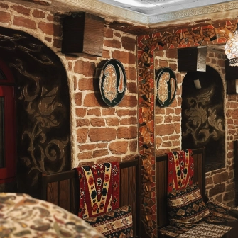 Sofra in Kyiv - cozy corner with brick walls, mirrors and traditional patterned cushions