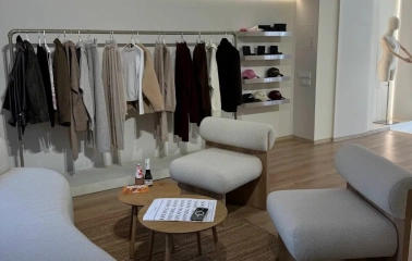 Concept 1 Boutique in Kyiv - cozy lounge area with modern white bouclé armchairs surrounded by fashion collections