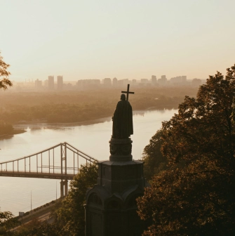 Monument to Vladimir the Great - silhouette of the statue overlooking the Dnipro River and bridge in golden light