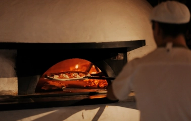Restaurant Tisto, Syr i Titka Bella - chef placing a pizza inside a wood-fired stone oven