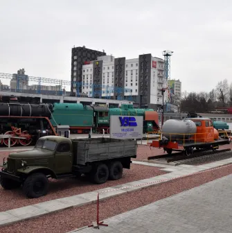 Railway Museum in Kyiv - open-air museum grounds displaying a variety of black steam engines, green locomotives, and vintage trucks on red gravel
