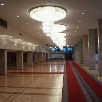 Palats Ukraina in Kyiv - spacious marble foyer with a long row of crystal chandeliers and a red carpet runner on the parquet