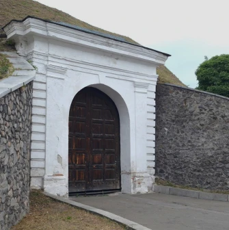 Kyiv Fortress in Kyiv - massive white stone arch with wooden gates built into the wall