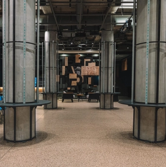 Teatr na Podoli in Kyiv - modern industrial foyer with concrete columns, blue chairs, and a logo wall