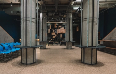 Teatr na Podoli in Kyiv - modern industrial foyer with concrete columns, blue chairs, and a logo wall