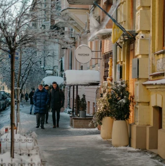 Pedestrians walking past the Matcher store on a snowy sidewalk in Kyiv