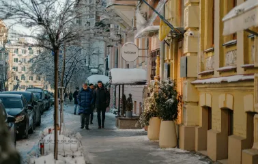 Pedestrians walking past the Matcher store on a snowy sidewalk in Kyiv