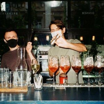 Bar Restaurant Kosatka - two bartenders wearing masks making and shaking drinks behind a counter