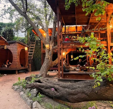 Chaguan in Kyiv - wooden two-story outdoor terrace structure among trees with guests