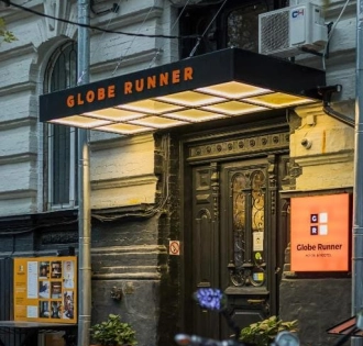 The entrance to the Globe Runner hostel in Kyiv with a sign and a black door