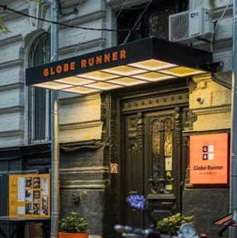 The entrance to the Globe Runner hostel in Kyiv with a sign and a black door
