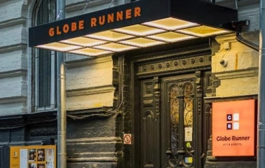The entrance to the Globe Runner hostel in Kyiv with a sign and a black door