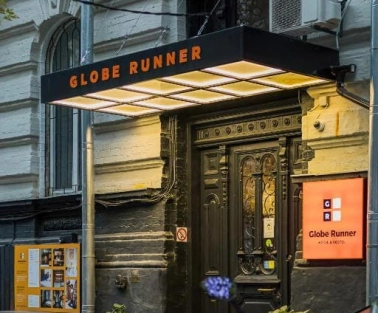 The entrance to the Globe Runner hostel in Kyiv with a sign and a black door