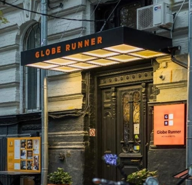 The entrance to the Globe Runner hostel in Kyiv with a sign and a black door