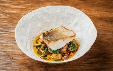 Restaurant Poltava - white fish fillet with crispy skin served in a bowl on a wooden table