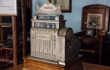 Pharmacy Museum in Kyiv - ornate antique silver "National" cash register standing on a wooden counter next to a retro telephone
